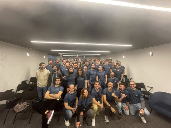 Fotografia de grupo da equipa da DXspark, com dezenas de colaboradores reunidos numa sala, a sorrir e a usar t-shirts da empresa. Representa o crescimento sustentável e a coesão da equipa ao longo do percurso da organização.